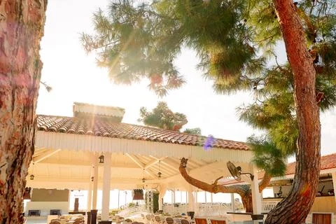 Place for dining is set up by sea with rows of empty tables  chairs. Sunlight Stock Photos