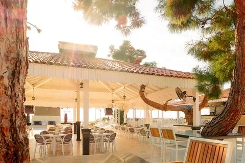 Place for dining is set up by sea with rows of empty tables  chairs. Sunlight 库存照片