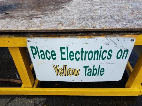 Place electronics on yellow table sign with table at recycling center Stock Photos