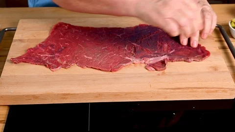 Place a fresh piece of beef roulade on a cutting board and cover with salt. Stock Footage 123575693