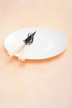 Place setting knife fork plate peach coloured bacground copy space Stock Photos
