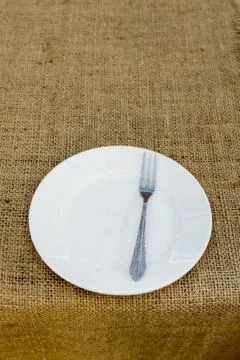 Place setting with plate and fork against brown plate mat Stock Photos