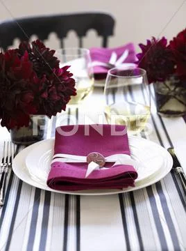 A Place Setting With A White Plate And A Pink Napkin