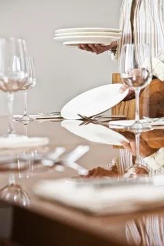 Place settings being arranged on a dining room table. Foto stock