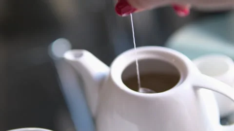 Place a tea bag in a white teapot. remove tea bags from teapot Stock Footage 301431906