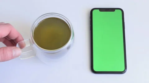 Place for tea drinking with smartphone on white table with green screen. Green Stock Footage 194173179