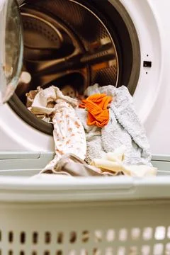 Place washed items from the washing machine into a basket Stockfoto's