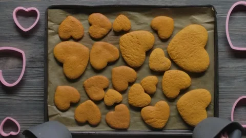 Placing baking tray with baked heart shaped gingerbread cookies Stock Footage 330790509