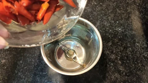 Placing boiled red chilies in a grinder Stock Footage 152397772