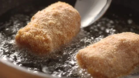 Placing breaded meatloaf in a pan with boiling oil. Stock Footage 258651331