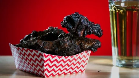 Placing a charred chicken wing into a paper container Stock Footage 327632166