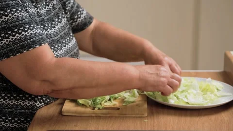 Placing chopped lettuce on plate for preparing Caesar salad. Arranging fresh Stock Footage 319162256
