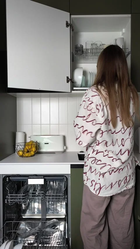 Placing clean plates into kitchen cabinet dryer rack after automatic dishwa.. Stock-Footage 346619963