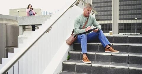 Placing coffee cup White man scribbling on tablet steps Latina woman with tote Video stock 335624584