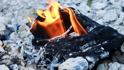 Placing coffee pot on top of small campfire with a rocky terrain in slow motion Stock Footage 131530363
