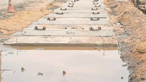 Placing concrete slabs to create a walkway over a waterlogged area at a Vídeo Stock 344675809