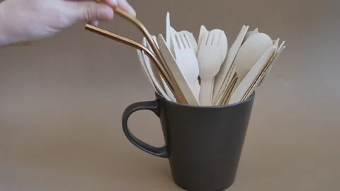 Placing copper drinking straws into a cup filled with wooden cutlery Stock-Footage 342501332