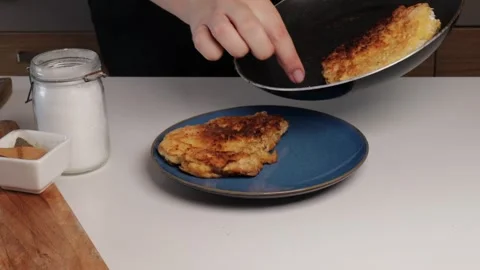 Placing crispy pork cutlets onto a blue plate on a kitchen counter with sea.. Stock Footage 318671829