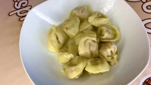 Placing dumplings into a deep white plate using a spoon. Hot dumplings. Stock-Footage 252749899
