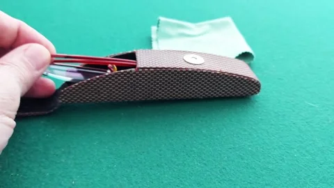 Placing Eyeglasses into Case on Green Tabletop Stock Footage 310933432