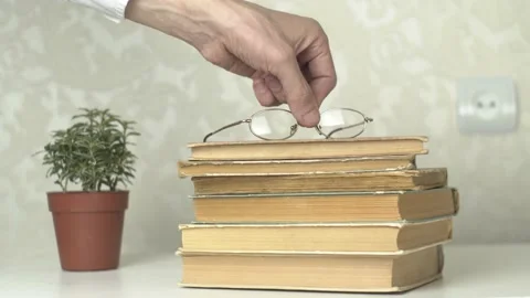 Placing Eyeglasses on Stack of Vintage Books Stock Footage 154659274