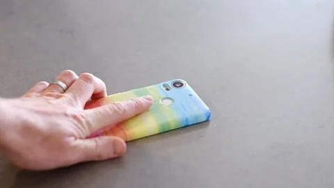 Placing face down onto kitchen worktop a rainbow mobile cell phone Stock Footage 94052259