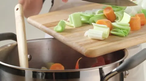 Placing finely chopped soup vegetables into a pan Stock Footage 24662895