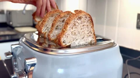 Placing four pieces of bread into toaster from side in modern kitchen interior Stock Footage 334560264