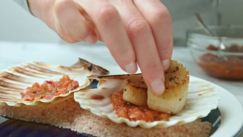Placing freshly cooked fried scallops into a shell in a serving plate in 4K. Stock Footage 142689250