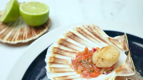 Placing freshly cooked fried scallops into a shell in a serving plate in 4K. Stock Footage 142689588