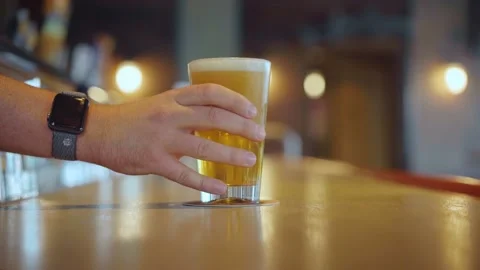 Placing full glass of beer with foam onto bar counter. Slow motion. Stock Footage 221410134