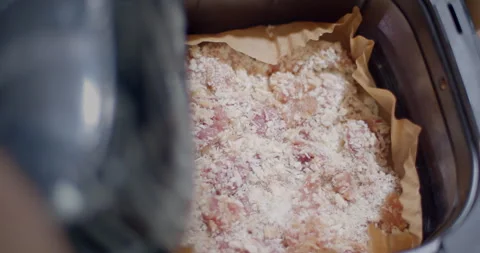 Placing a full tray of breaded pork pieces into an oven preparing Stock Footage 312311745