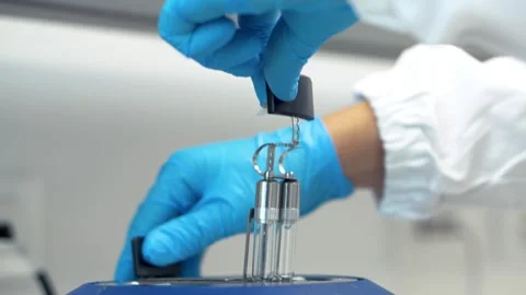 Placing glass containers into a device for determining the softening of wax Stock Footage 310681435