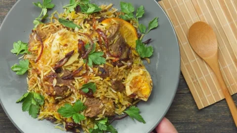 Placing a Gray Plate of Beef Biryani onto a Table, Top View Stock Footage 311017724