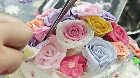 Placing a hand-piped buttercream rose onto a cake with lifter scissors. Vidéo 344746306