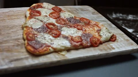 Placing a hot heart shaped pizza on the wooden board. Surprise meal for a loved Stock Footage 146661545