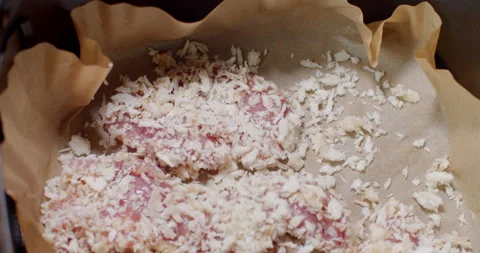 Placing individually coated pork chunks into a lined tray, preparing for baking. Stock Footage 312312052