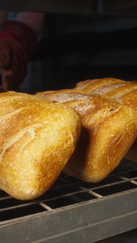 Placing Large Freshly Baked Bread on Bakery Rack Slow Motion Stock Footage 345878701