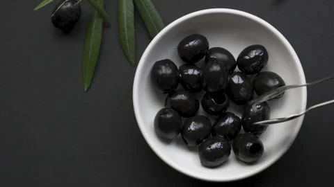Placing last black olive into white bowl on black background 4k 120fps Vídeo Stock 334638145