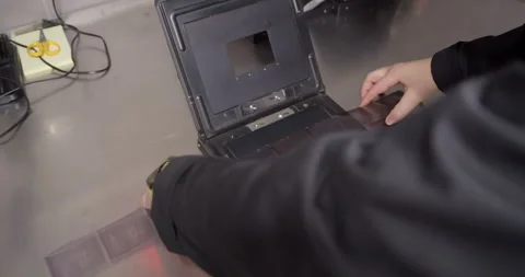 Placing medium format film into negative carrier for darkroom printing. 库存影片 313980730