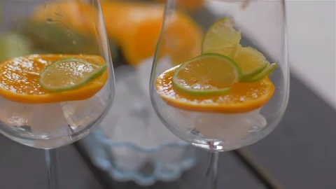 Placing orange slice in a glass with ice . Preparing cocktails Video stock 110046785