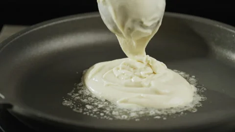 Placing the pancake batter on the pan. Baking pancakes at home. American pancake Stock Footage 266818617