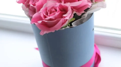 Placing pink roses with beautifully wrapped gift against a slate background Stock Footage 68394792
