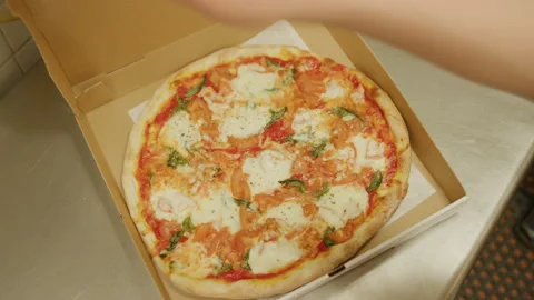 Placing pizza in delivery box and slicing at italian restaurant Stock Footage 238969197