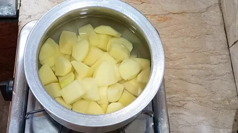 Placing Pot of Potato Chunks with Water on Stove and Covering to Boil, Kitchen  Stock Footage 329094876