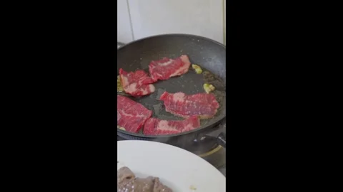 Placing raw beef slices into frying pan during cooking close up Video stock 331196414