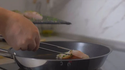 Placing raw fish fillets in a heated pan Stock Footage 111969350