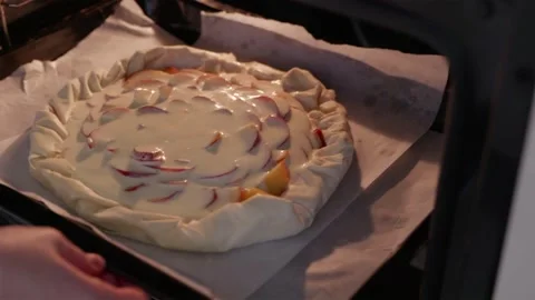 Placing raw nectarine galette into hot modern oven for baking Stock Footage 336848405