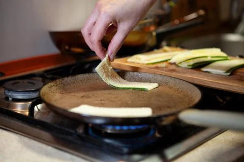 Placing raw zucchini slice on frying pan Stock Photos