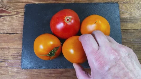 Placing red and orange tomatoes to black slate flat plate 動画素材 339794373